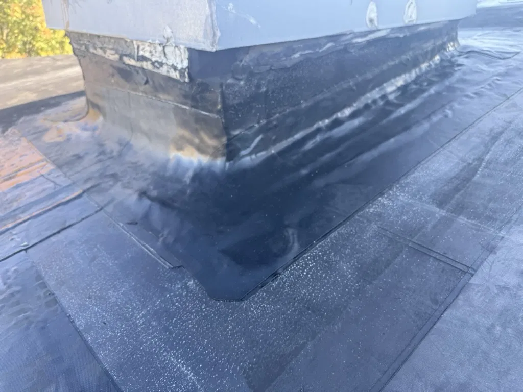 Metal wall and flat roof junction sealed against leaks